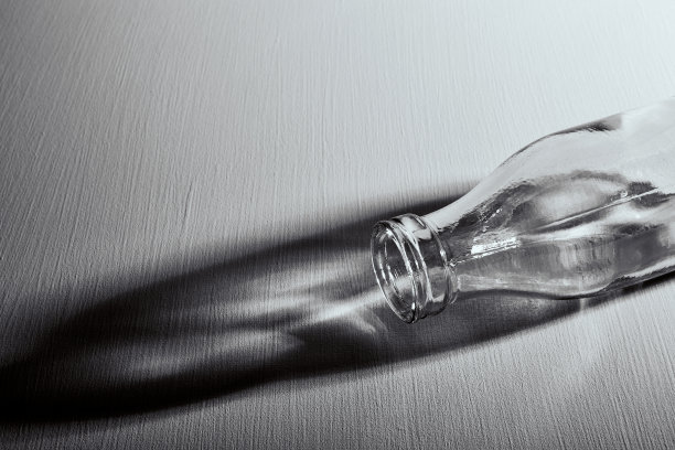 桌子上有一个空玻璃瓶。副本的空间。图形静物与黑白颜色的光和阴影。可回收材料或酗酒问题的概念。抑郁状态图片下载
