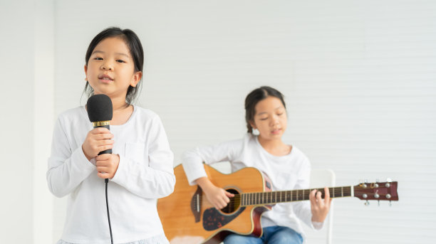 可爱的孩子们唱着歌，看着镜头，孩子们弹着吉他。亚洲儿童在小学校的教育教室学习音乐和唱歌图片下载