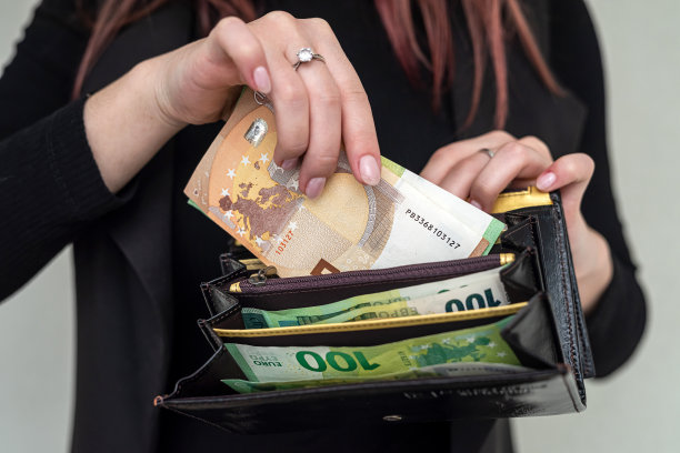 一位年轻漂亮的黑衣女孩想从一家服装店的钱包里掏出欧元。图片下载