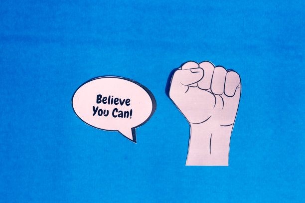 坚定的人的手与动机文本讲话气泡孤立在蓝色背景上。概念形象表明，第一件事就是相信自己能够实现自己的目标。图片下载