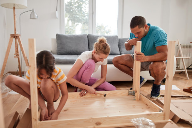 母亲、父亲和女儿正在组装新家具——搬进新家。图片下载