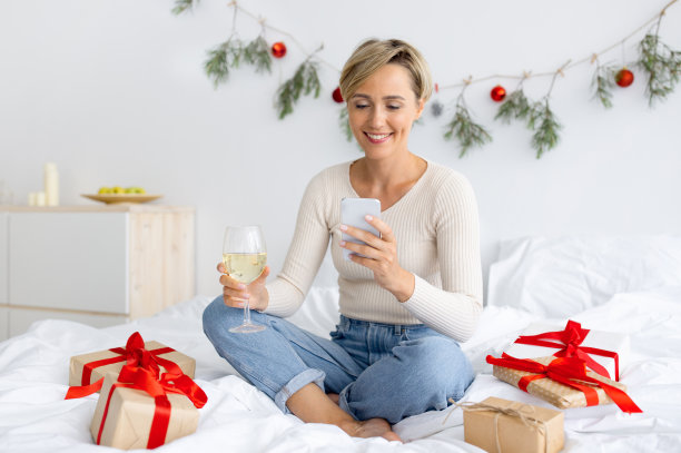 快乐的女士在圣诞节喝酒时用手机图片下载
