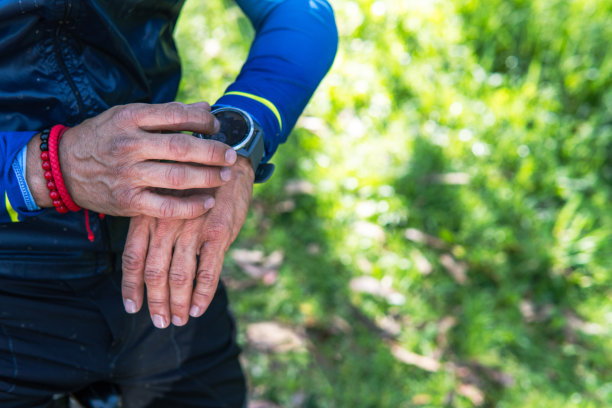 一个跑步者的手的特写，他正在看他的智能手机上的gps应用程序在森林里越野跑图片下载