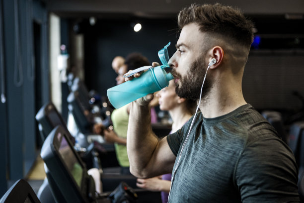年轻人在跑步机上补水图片下载