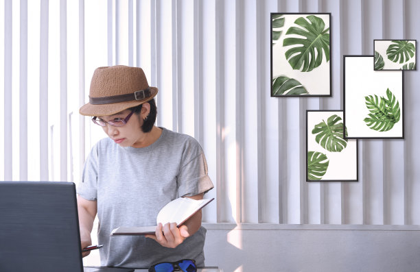 亚洲中年女性时尚设计师，穿着复古服装，在家庭办公室工作时使用笔记本电脑图片下载