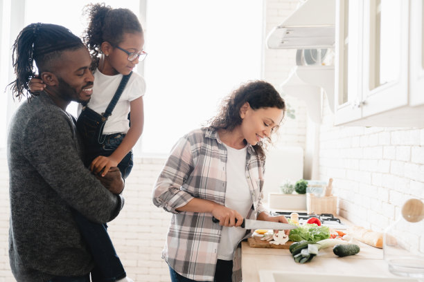母亲在厨房切菜做沙拉，父亲和女儿帮忙准备午餐和晚餐图片下载
