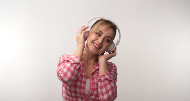 年轻女子戴着耳机听音乐，背景是白色的。图片下载
