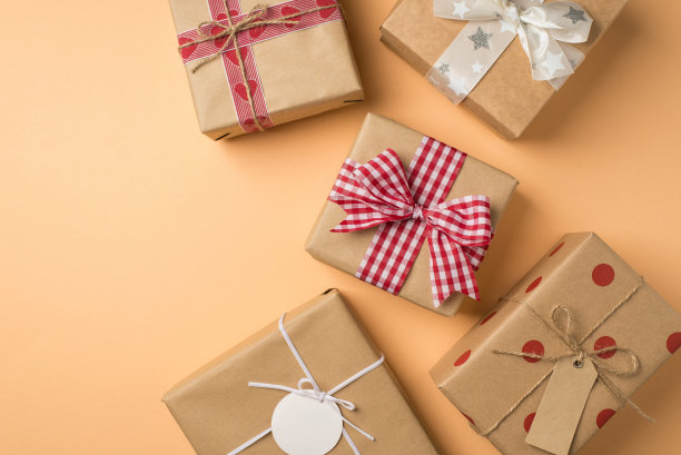 俯视图照片的情人节装饰，许多牛皮纸礼品盒与丝带和缠绕蝴蝶结孤立的米色背景copyspace图片下载