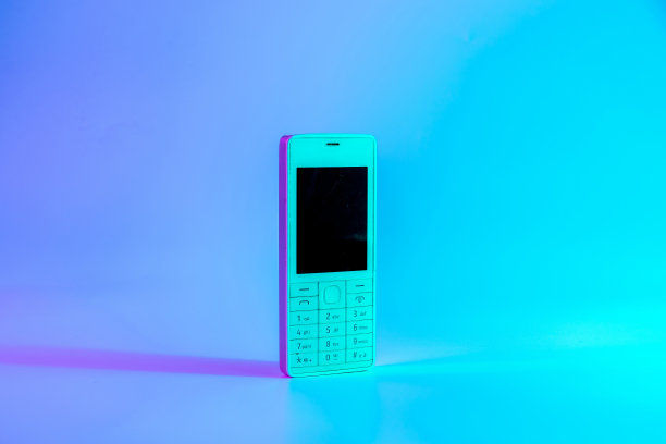 复古手机的概念。白色的旧手机在霓虹灯下，粉红色的蓝光。复古的波。波普艺术。最小的思想概念。图片下载