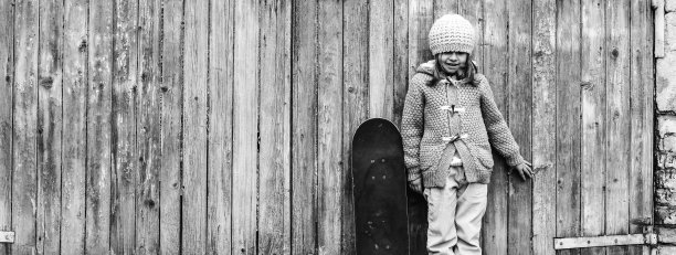 水平横幅或头部与可爱的小女孩在冬季羊毛衣服与滑板，而站在垃圾木制背景-活动和好玩的童年-复制空间的概念图片下载