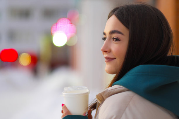 冬天的肖像年轻美丽的女孩在城市街道户外带走一杯咖啡。图片下载