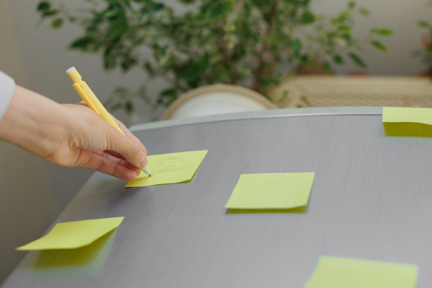 一名妇女在冰箱上的彩色贴纸上做笔记。给丈夫和孩子的提醒或便条图片下载