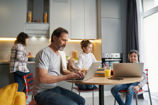 男人和男孩坐在电脑前，而女人在做饭图片下载
