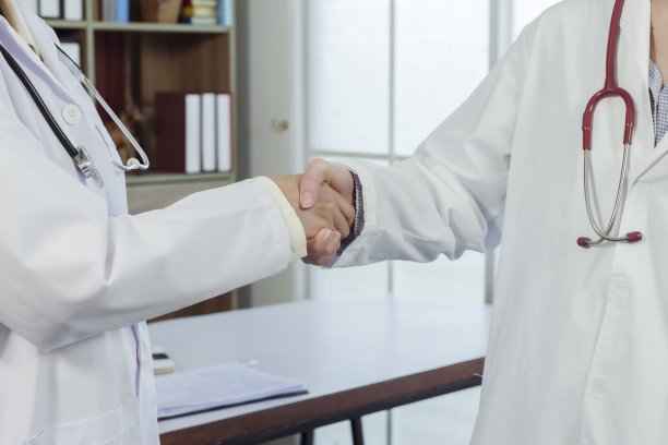 4k，两个穿着白衬衫的亚洲女医生手牵着手。祝贺双方通过两家医院的合作，使活动取得圆满成功。图片下载