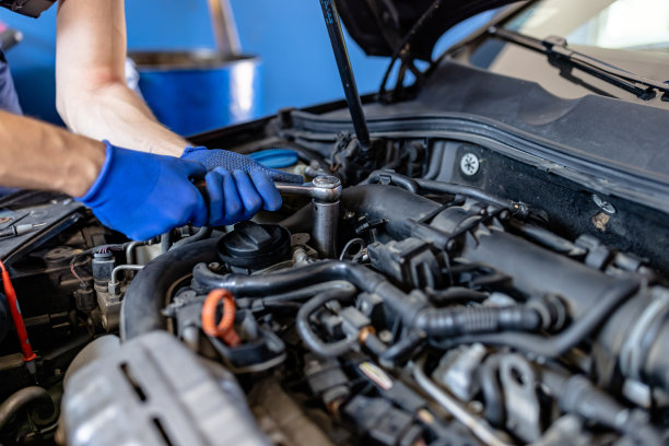 年轻的男性汽车修理工正在和机械师一起解决汽车发动机的问题。图片下载