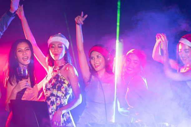 活跃的漂亮的年轻DJ女人的肖像在激光灯光背景下播放音乐图片下载