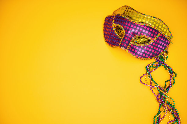 狂欢节背景与彩色珠子和威尼斯面具在黄色背景图片下载