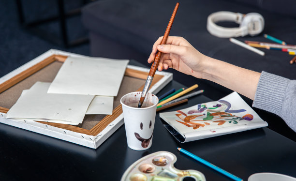 特写镜头，一个女人把刷子浸入一杯水里。图片下载