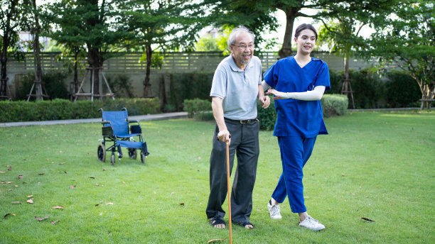 亚洲年轻漂亮的女护士在养老院照顾老人。护理医生为年老的病人提供物理治疗，让他们在后院用助行器或拐杖练习走路图片下载