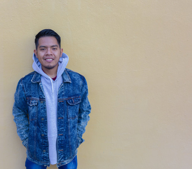 一个墨西哥人微笑着看着黄色墙壁前的镜头图片下载