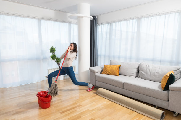 快乐的学生或商人打扫房间，用拖把一样的麦克风唱歌，在擦地板的时候玩得很开心。年轻女性做家务，家务观念图片下载