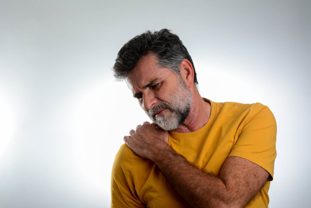 英俊的男子与胡子孤立的灰色背景遭受疼痛的肩膀。图片下载