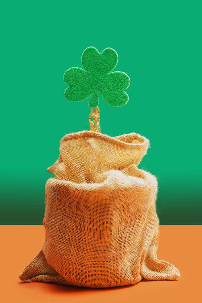 摘要金宝最小概念。绿色三叶草从宝袋里拿出一条金色的链子。柔和的绿色和陶土背景。图片下载