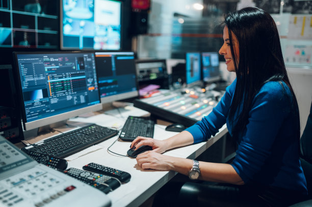 一位中年妇女在电视台的控制室里使用设备图片下载
