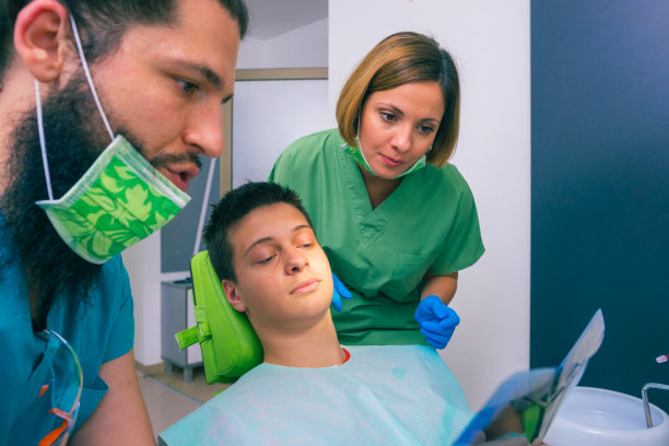 男女牙医在牙科诊所给一个小男孩病人看他的牙齿x光图像。图片下载