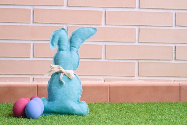 棉织的小兔子和复活节彩蛋在草地上图片下载
