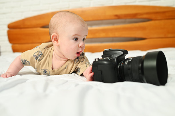 白色的床上放着一架现代相机的小孩或男婴图片下载