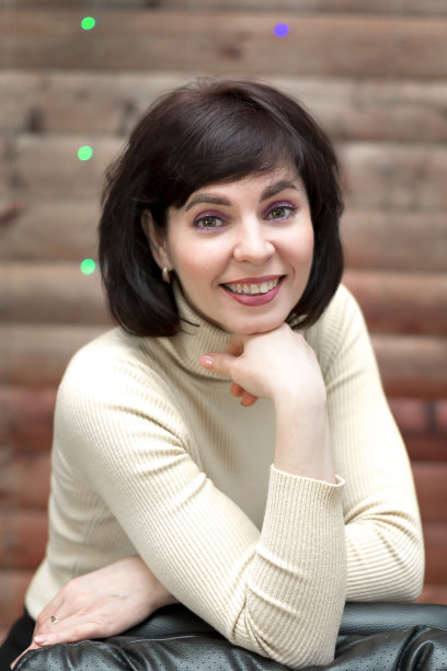 一个深色头发的女人穿着一件带领的黄色夹克，斜靠在一把高皮椅上图片下载