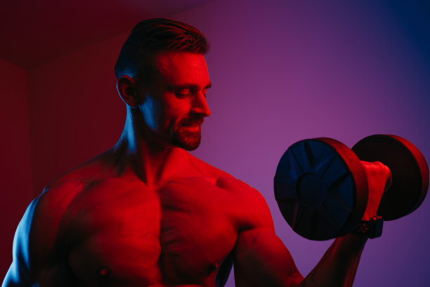 一个肌肉发达的男人在蓝色和红色灯光下做二头肌卷曲的特写照片图片下载