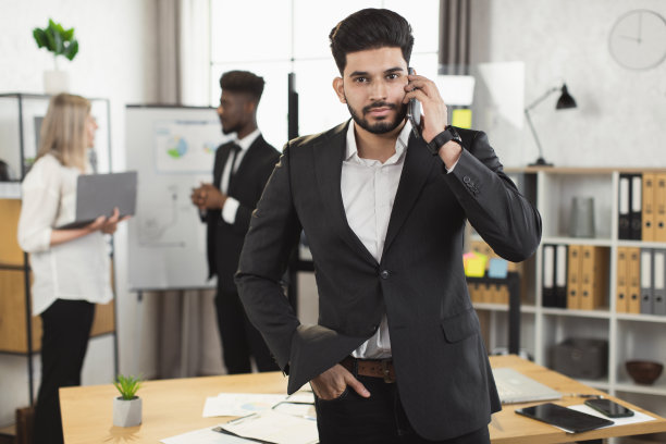 自信的印度西装男在办公室用手机聊天图片下载