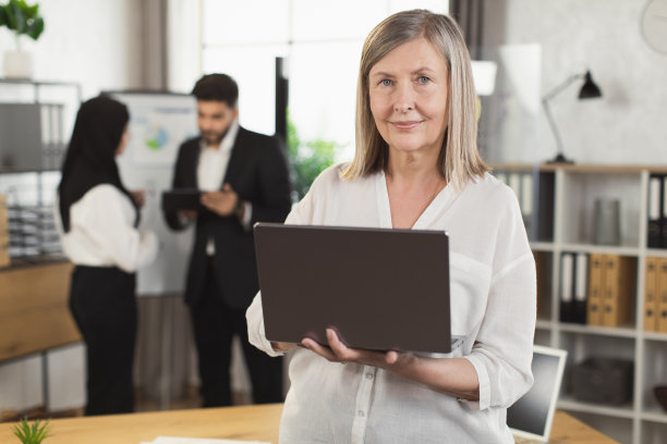 白种老年妇女拿着笔记本电脑在办公室摆姿势图片下载