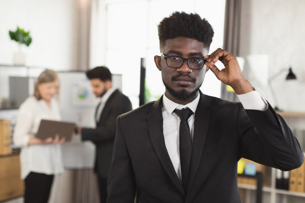 穿着西装、戴着眼镜、面带微笑的非洲人在办公室摆姿势图片下载