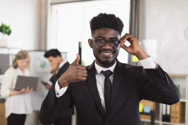 穿着西装、戴着眼镜、面带微笑的非洲人在办公室摆姿势图片下载