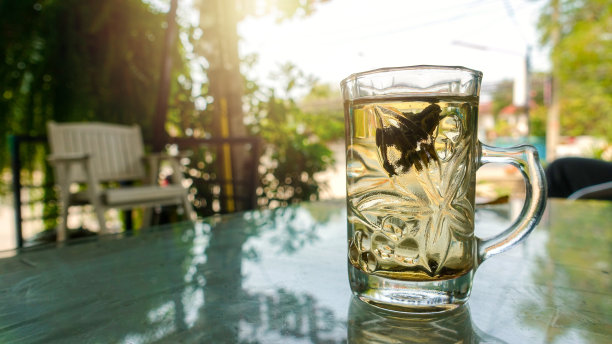 早上用透明玻璃盛着热茶，放在木桌上。图片下载