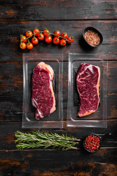 纽约牛排切在塑料包装，在旧的深色木制桌子背景，俯视图平躺图片下载