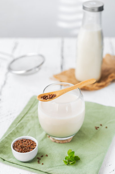 亚麻籽牛奶放在白色木桌上，牛奶瓶，亚麻籽，薄荷叶，筛子图片下载