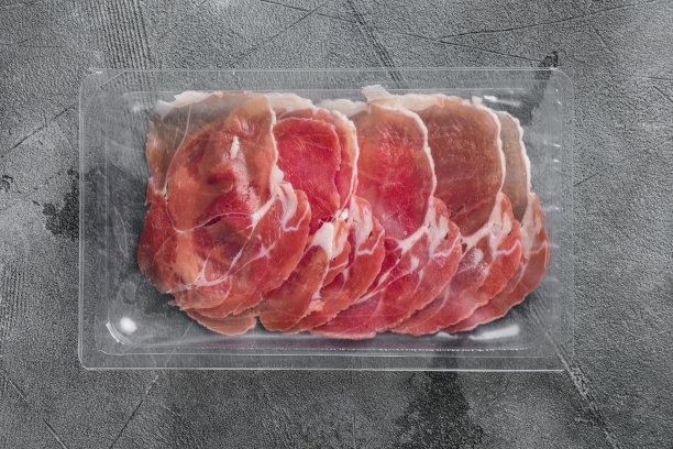 真空包装的火腿片，在灰色的石头桌子背景上，俯视图平铺图片下载