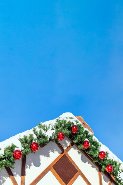 木制的屋顶装饰着圣诞玩具，红色的球，花环树枝覆盖着雪图片下载