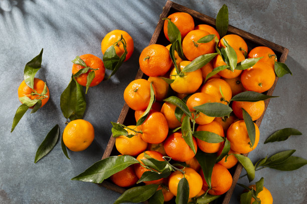 新鲜的柑橘水果或柑橘与叶子在木制盒子，俯视图图片下载