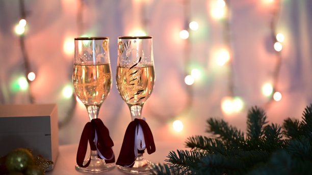 在一棵装饰过的圣诞树的背景上，几杯闪闪发光的香槟。图片下载