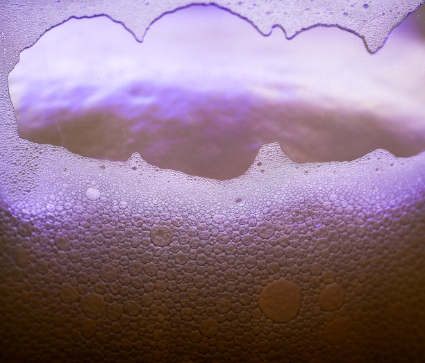 在摄影棚里，玻璃杯中的啤酒泡沫和气泡被拍摄下来图片下载