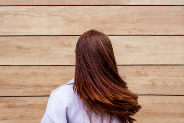 一个年轻的女人摆弄着她的头发。后视图图片下载