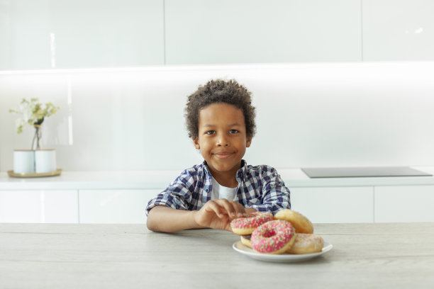 快乐的小男孩在白色背景上玩甜甜圈图片下载