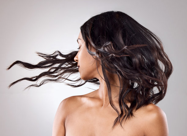 一个美丽的年轻女子在灰色的背景下摆姿势图片下载