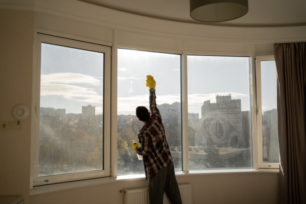 男人在家擦窗户，便服穿衬衫，黄色橡胶手套，家居清洁概念。图片下载