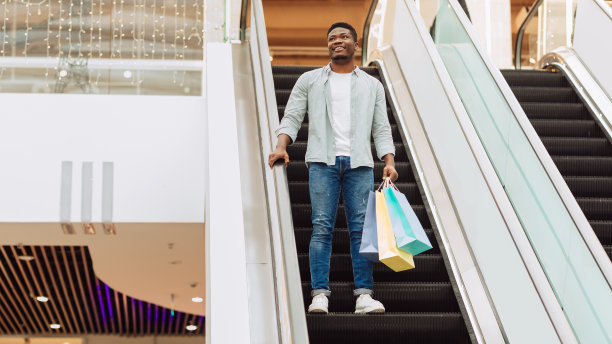 快乐的黑人拿着购物袋上自动扶梯图片下载
